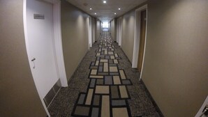 A hotel hallway with carpeted floors, white doors, and a sign indicating a laundry room. - Quality Inn (Barrie)