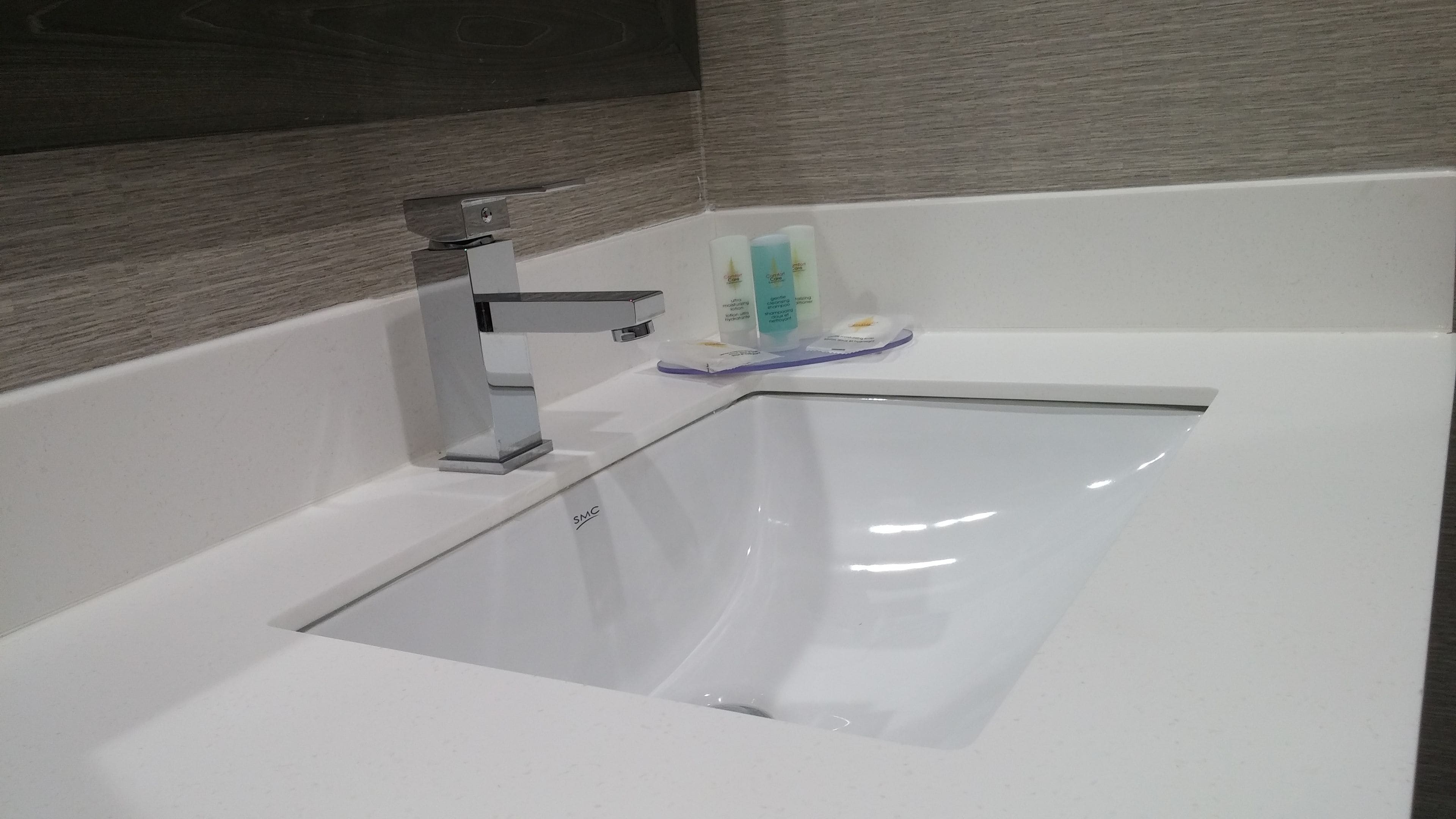 Un baño moderno con una bañera blanca, un grifo cromado y artículos de tocador al borde.