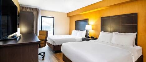 Une chambre d’hôtel avec deux lits, un bureau, une chaise et un téléviseur.