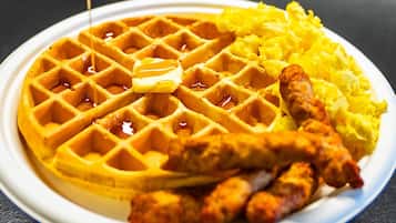A plate with a waffle, scrambled eggs, and sausage.