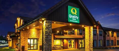A hotel with a prominent "Quality Inn by Choice Hotels" sign, featuring a stone facade and a covered entrance area.