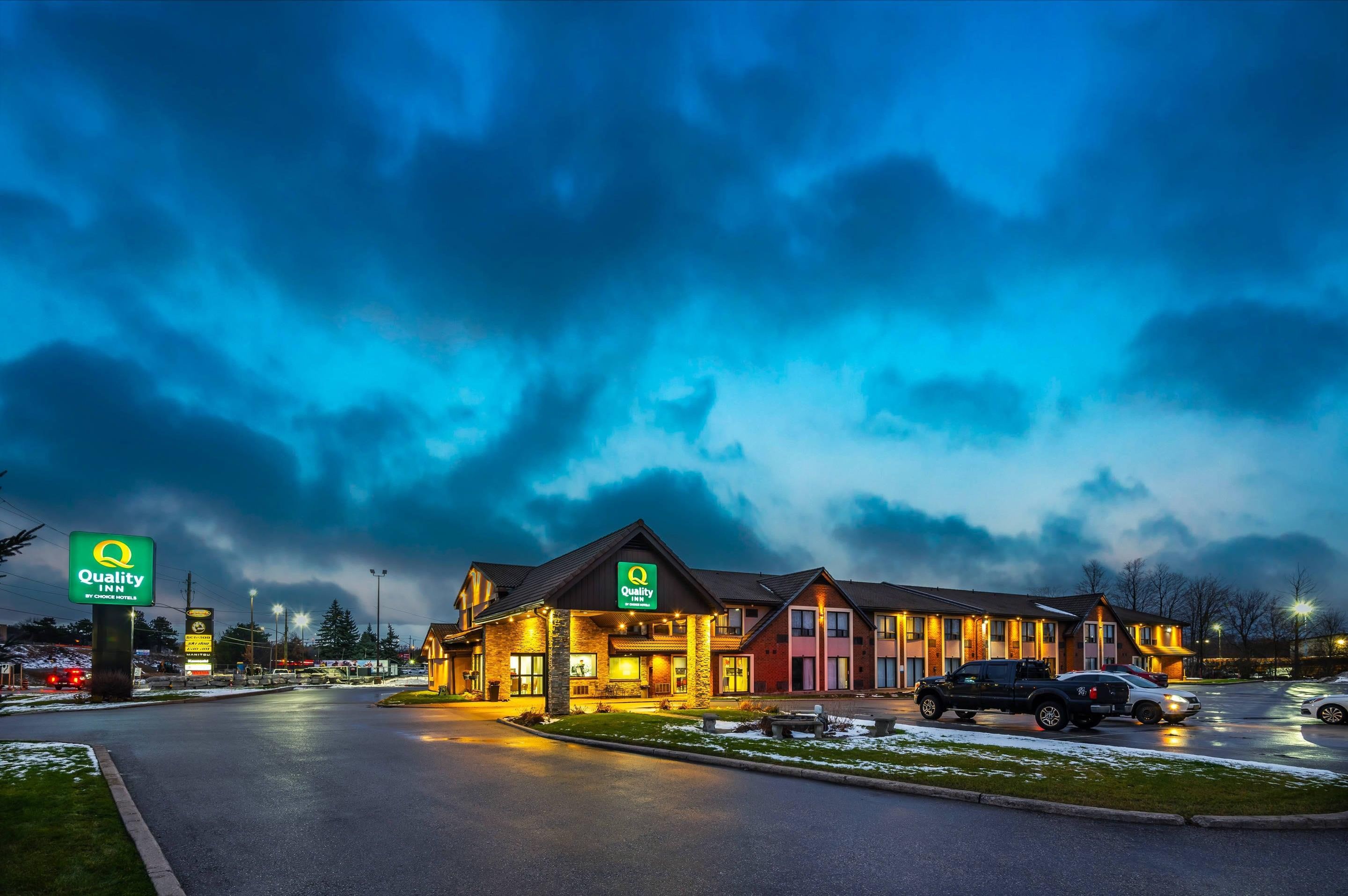 A Quality Inn hotel with a traditional design, featuring a central building with multiple rooms and a parking lot.