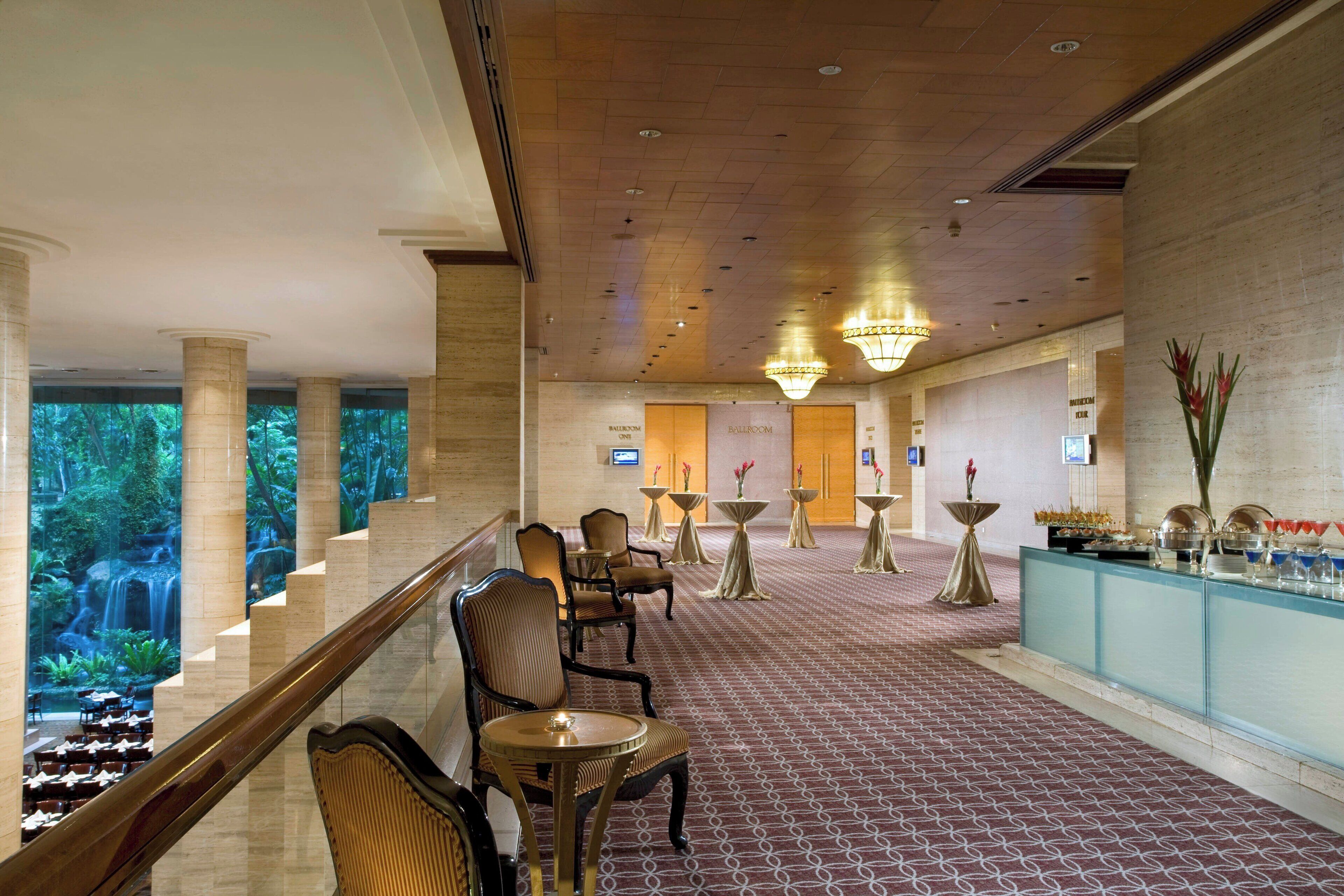 A hotel lobby with a grand staircase, seating area, and a view of a waterfall.