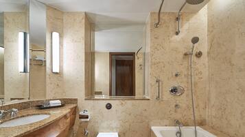 A modern bathroom with a large sink, mirror, and shower area.