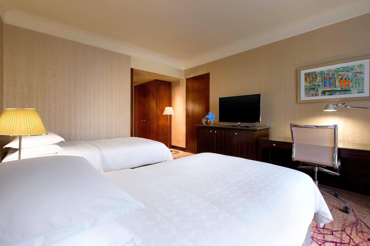 Una habitación de hotel con dos camas, una televisión, un escritorio y una silla.