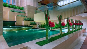 Un área de piscina interior moderna con jardineras escalonadas y una fuente central.