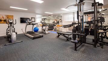 Ett gym med löpband, crosstrainers, roddmaskin, fria vikter och en träningsbänk.