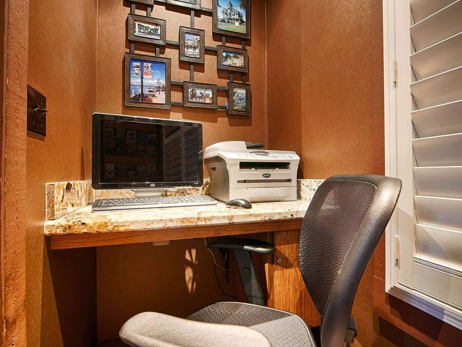 Un espacio de trabajo en casa con una computadora de escritorio, una impresora y una silla.