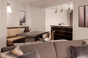Um interior moderno com sofá, um banco, uma mesa de jantar e luminárias pendentes.
