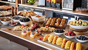 Buffet com diversas opções de comida, incluindo frutas, doces e bebidas.