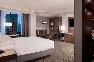 Una habitación de hotel con una cama grande, un escritorio, un sofá y un televisor.