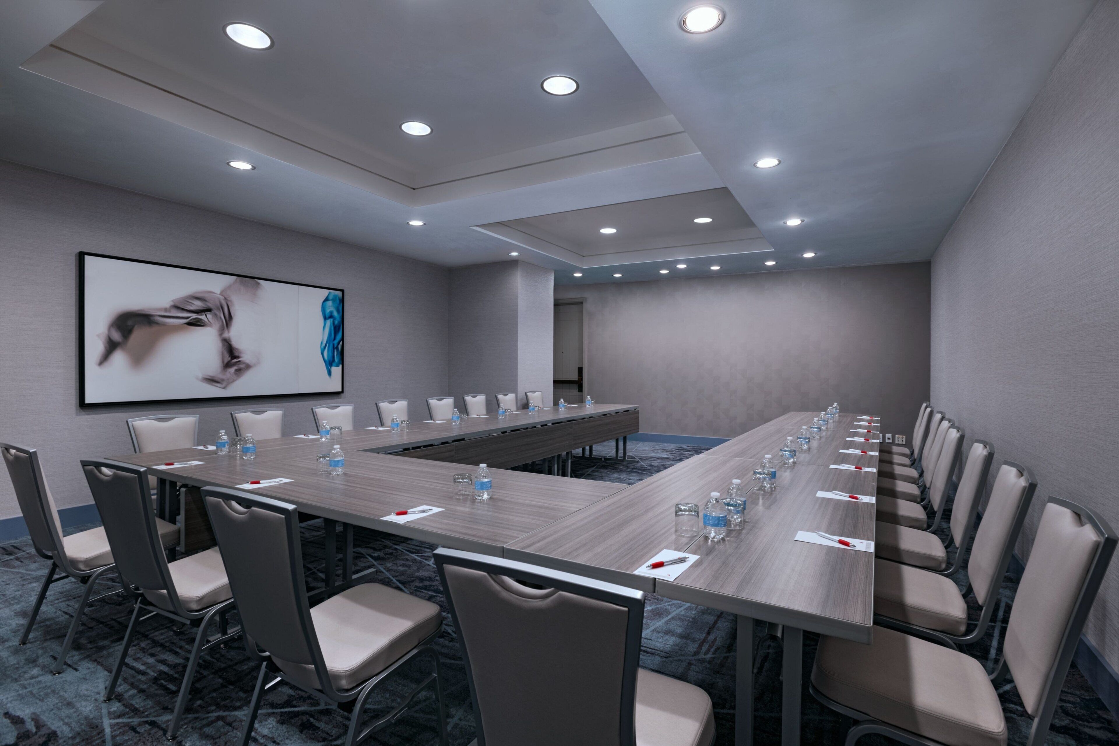 A conference room with a long table, chairs, and a projector screen displaying an image.