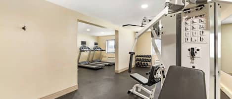 Un gimnasio con cintas de correr, máquinas de pesas y mancuernas.