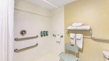 Baño accesible para personas con movilidad reducida, con barras de apoyo, ducha, inodoro y silla.