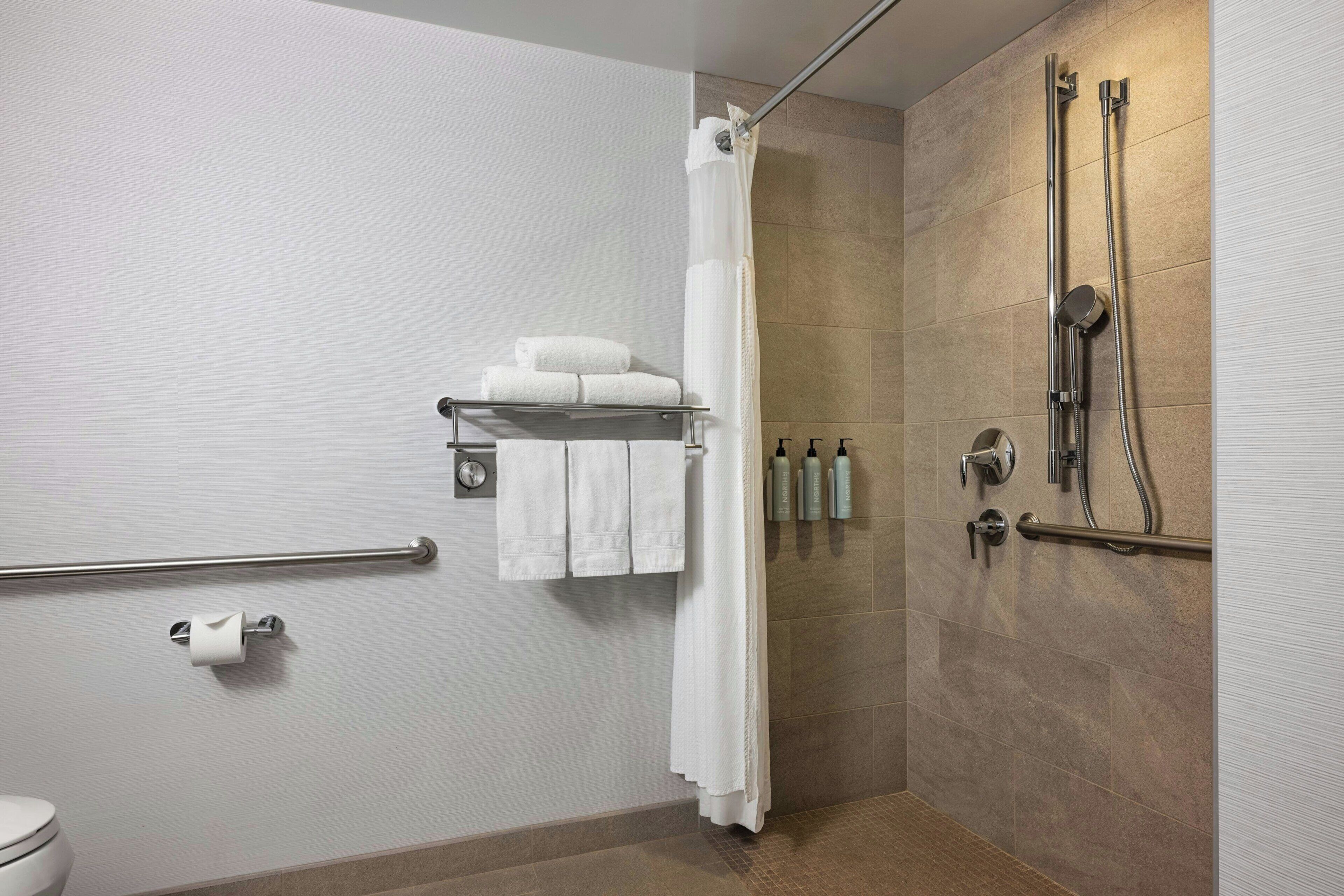 A modern bathroom with a shower, toilet, and towel rack.