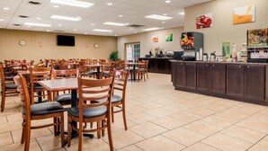 A spacious dining area with multiple tables and chairs, a coffee station, and a counter with various food and drink options. - Quality Inn Huntingburg - Jasper (Huntingburg)