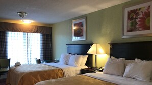 A hotel room with two beds, a nightstand with a lamp, a painting on the wall, and a window with curtains. - Quality Inn Huntingburg - Jasper (Huntingburg)