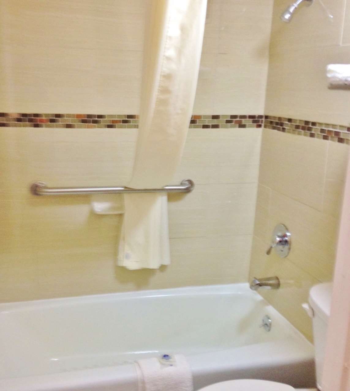 A bathroom with a bathtub, a shower curtain, a towel rack, and a toilet.