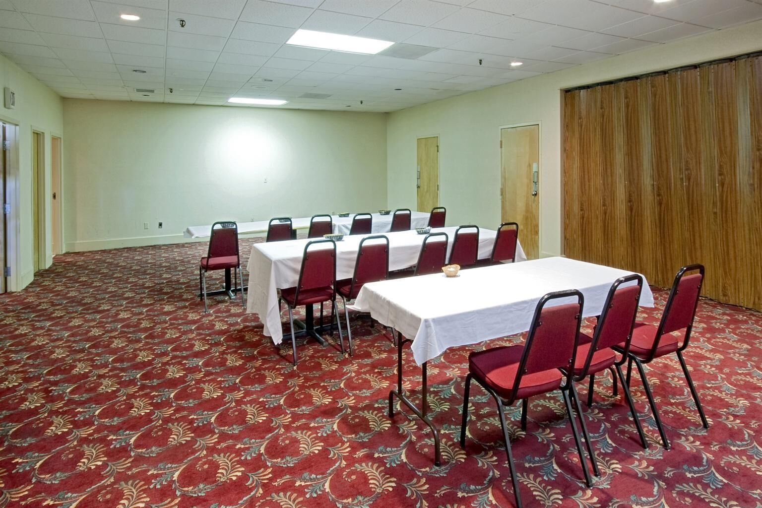 A conference room with a long table, red chairs, and a patterned carpet.