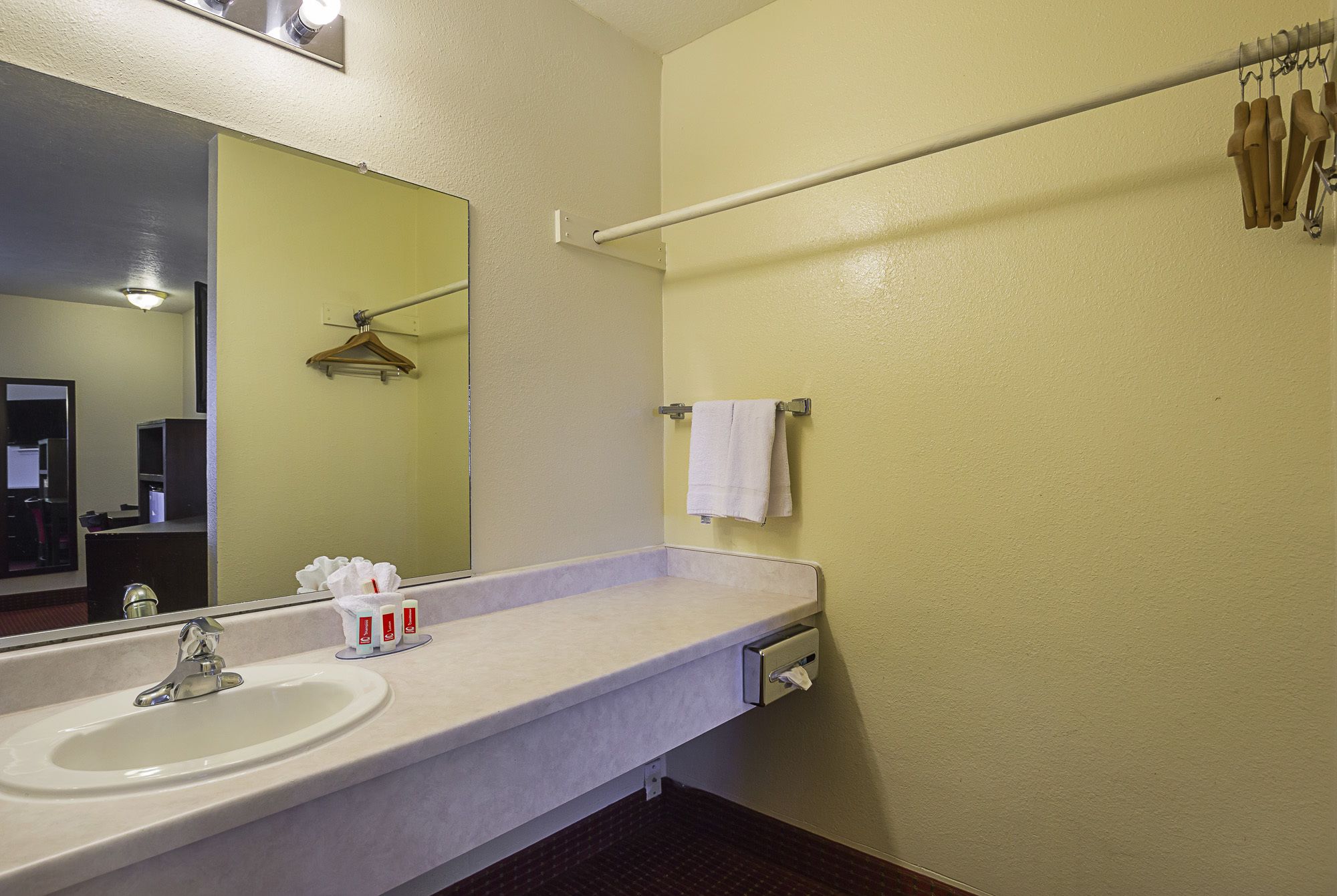 A bathroom with a sink, mirror, towel rack, and toiletries.