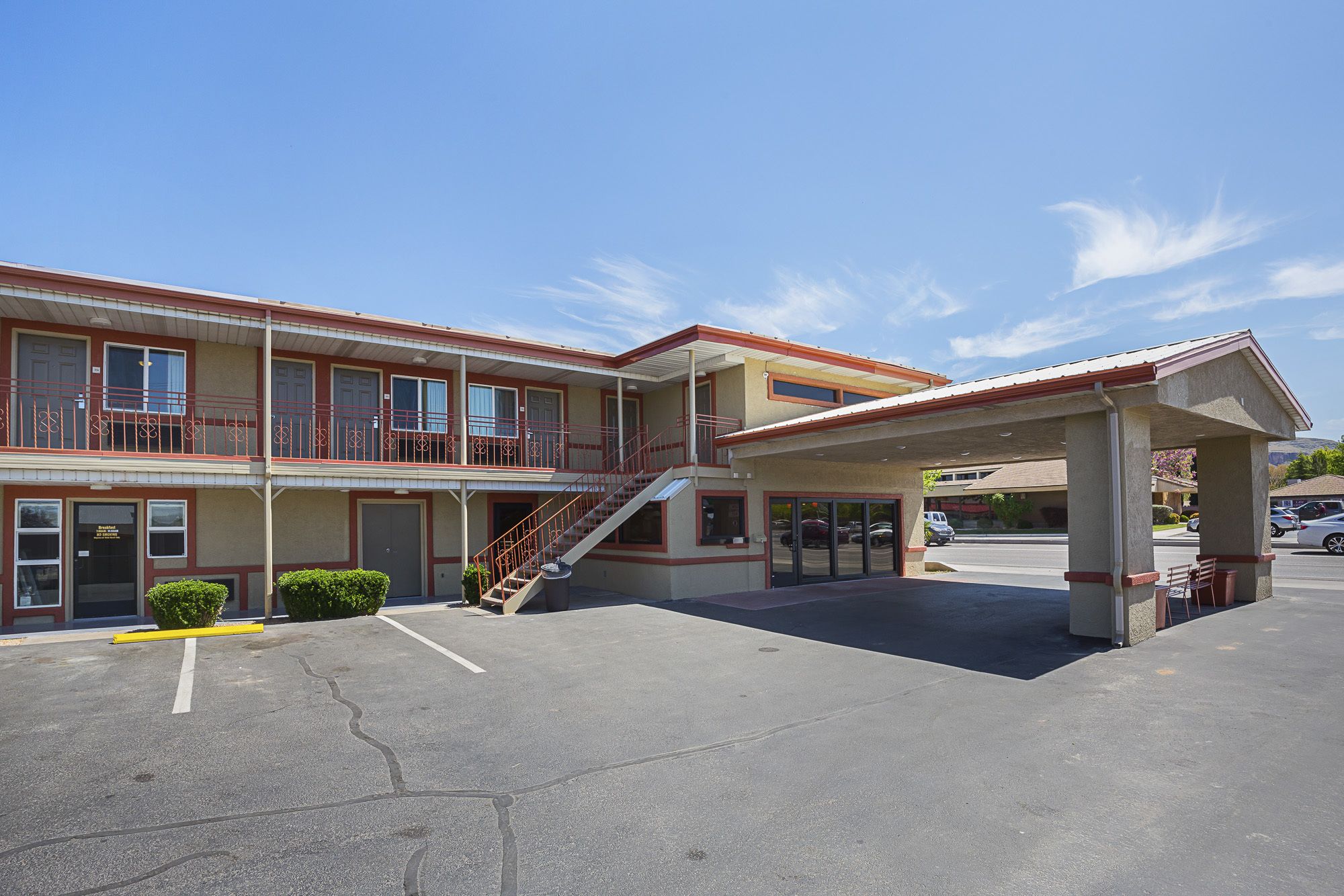 A two-story motel with a covered parking area and a staircase leading to the upper floor.