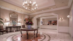 A lobby with a round table, a chandelier, a large mirror, and a reception desk. - The Sutton Place Hotel Vancouver (Vancouver)