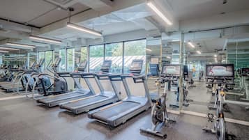 Un gimnasio con cintas de correr, bicicletas estáticas y equipo de ejercicio.