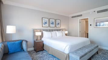 Une chambre d’hôtel avec un grand lit, une table de chevet avec des lampes, un banc et un mur orné de trois tableaux encadrés.