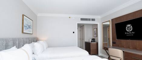 Una habitación de hotel con dos camas, un escritorio, una silla, un televisor y un cuadro en la pared.