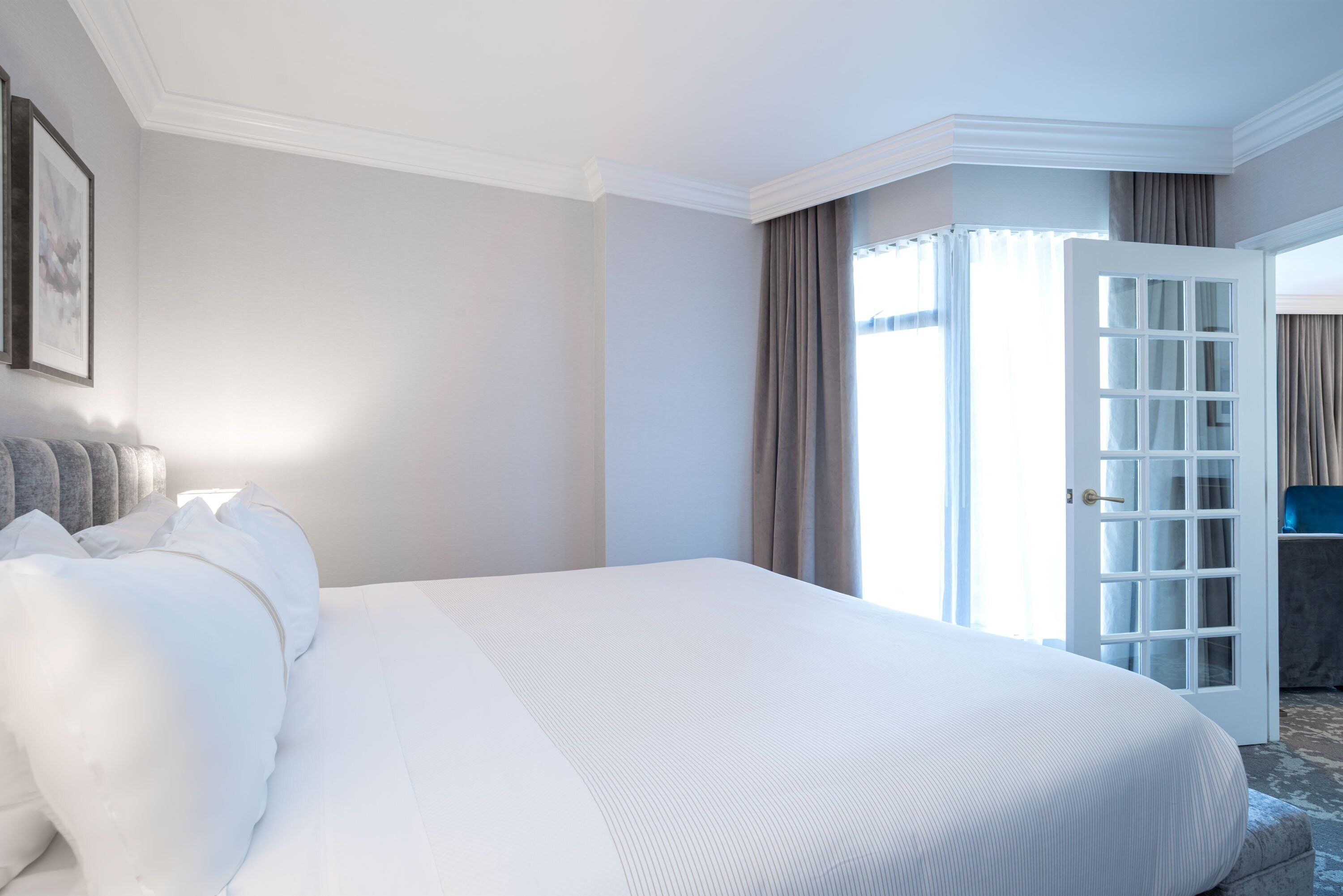 A hotel room with a large bed, a wardrobe, and a door leading to a balcony.
