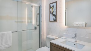 A modern bathroom with a glass shower enclosure, a white toilet, and a sink with a wooden vanity.