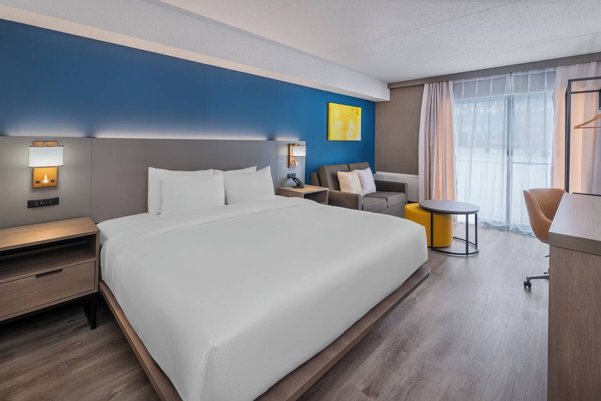 Une chambre d’hôtel avec un grand lit, un bureau, une chaise et une petite table.