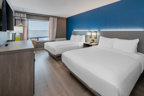 A hotel room with two beds, a desk, a chair, a hanging coat rack, and a window with curtains.