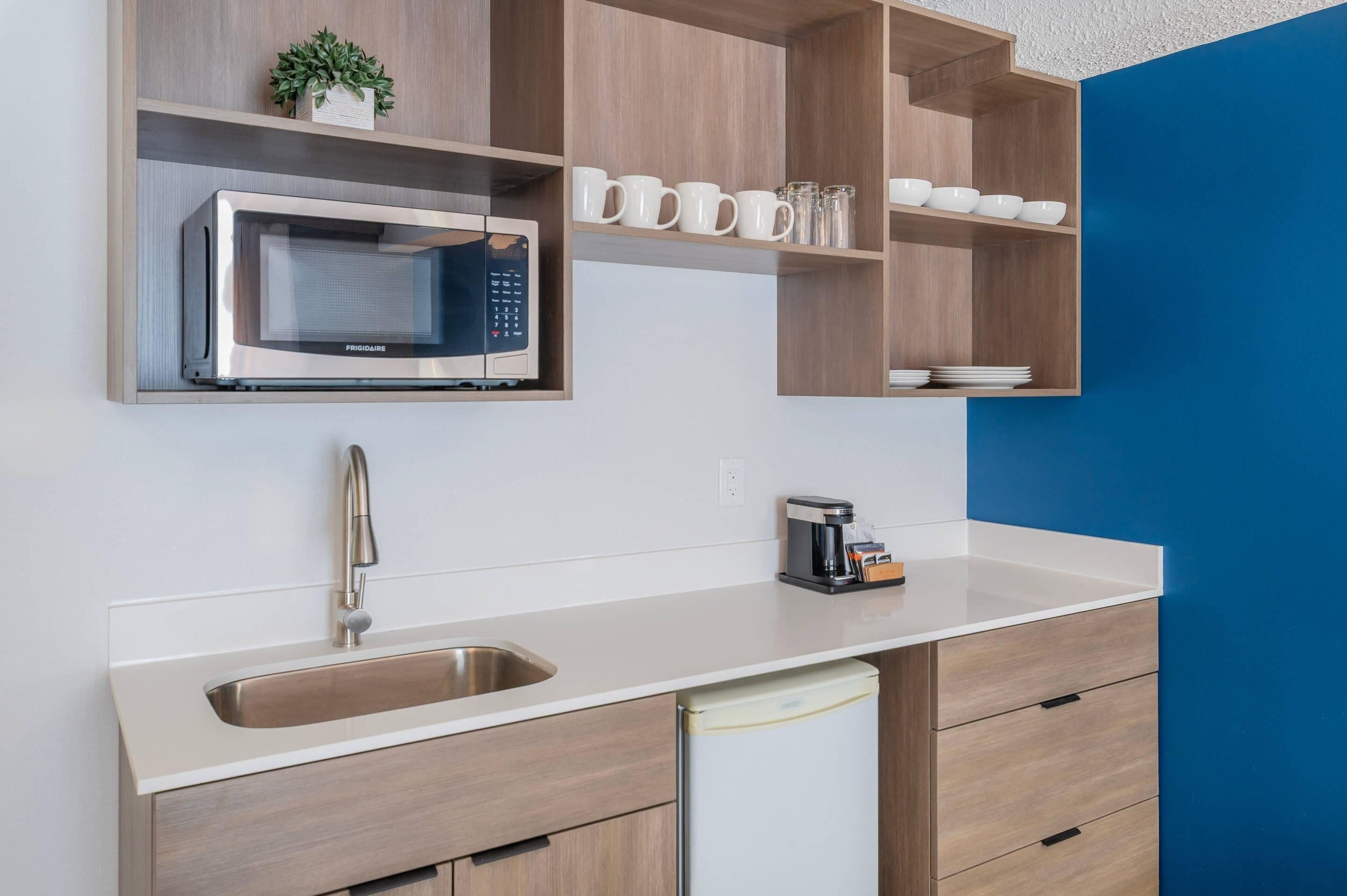Una cocina moderna con microondas integrado, cafetera y lavabo.