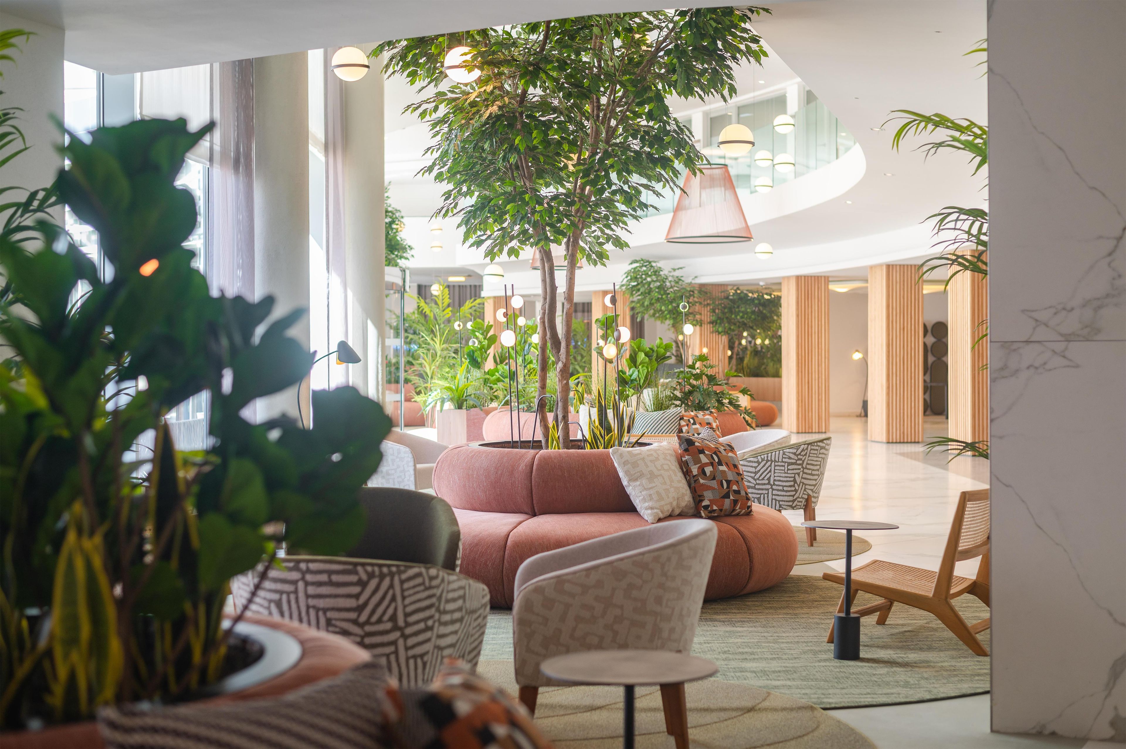 Un espacio interior moderno con una zona de estar, un árbol y vista al interior.