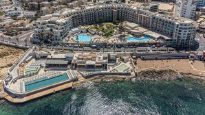 Un resort con varias piscinas, una zona de playa y vistas al mar.