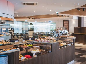 A buffet area with various food stations and a seating area in the background. - DoubleTree by Hilton Malta (St. Paul's Bay)