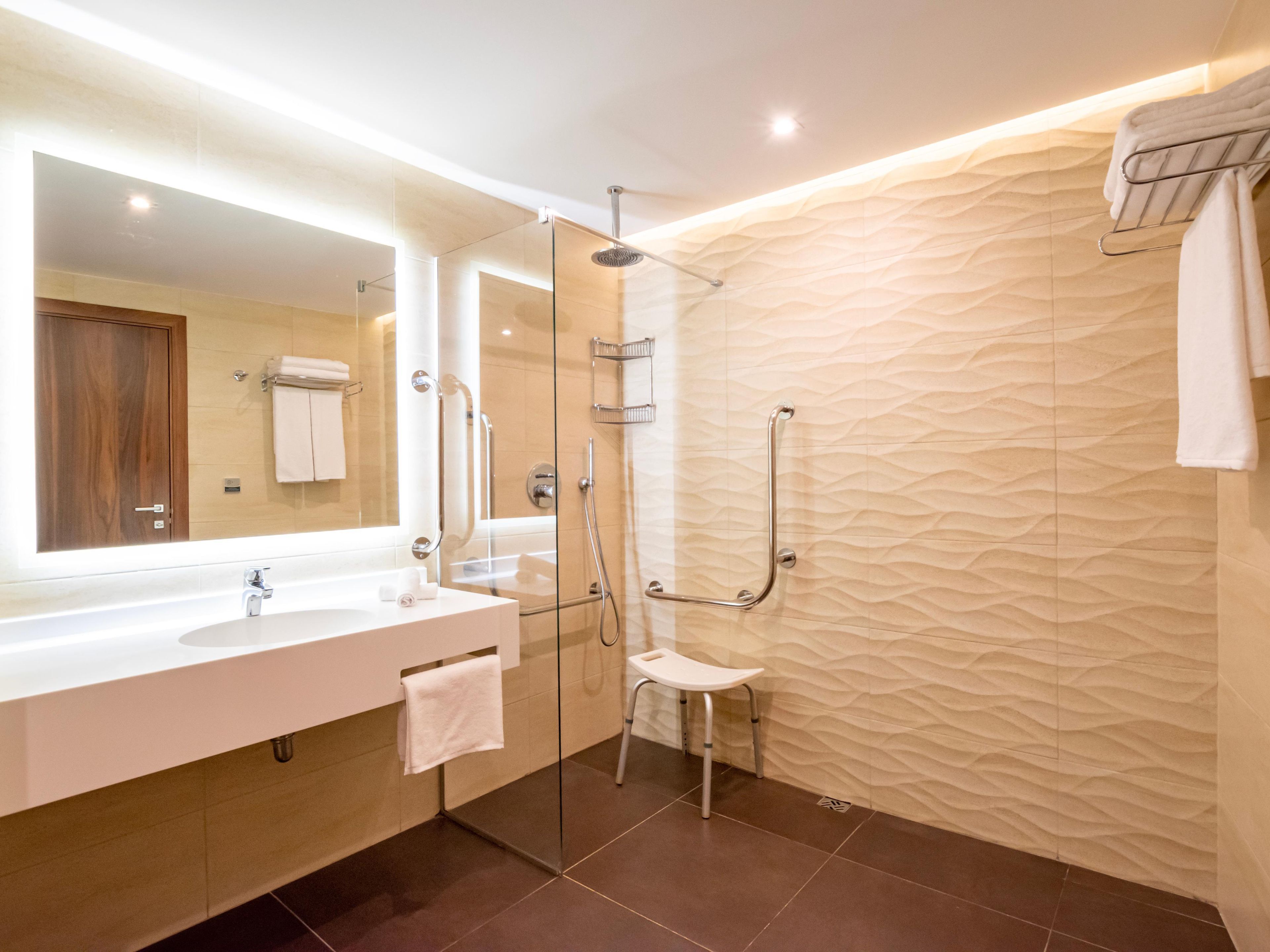 A modern bathroom with a glass-enclosed shower, a vanity with a mirror, and a textured wall.