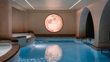 A swimming pool with a circular skylight, steps leading into the water, and arched alcoves.