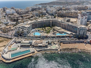 A resort with multiple swimming pools, a beach area, and a view of the sea.
