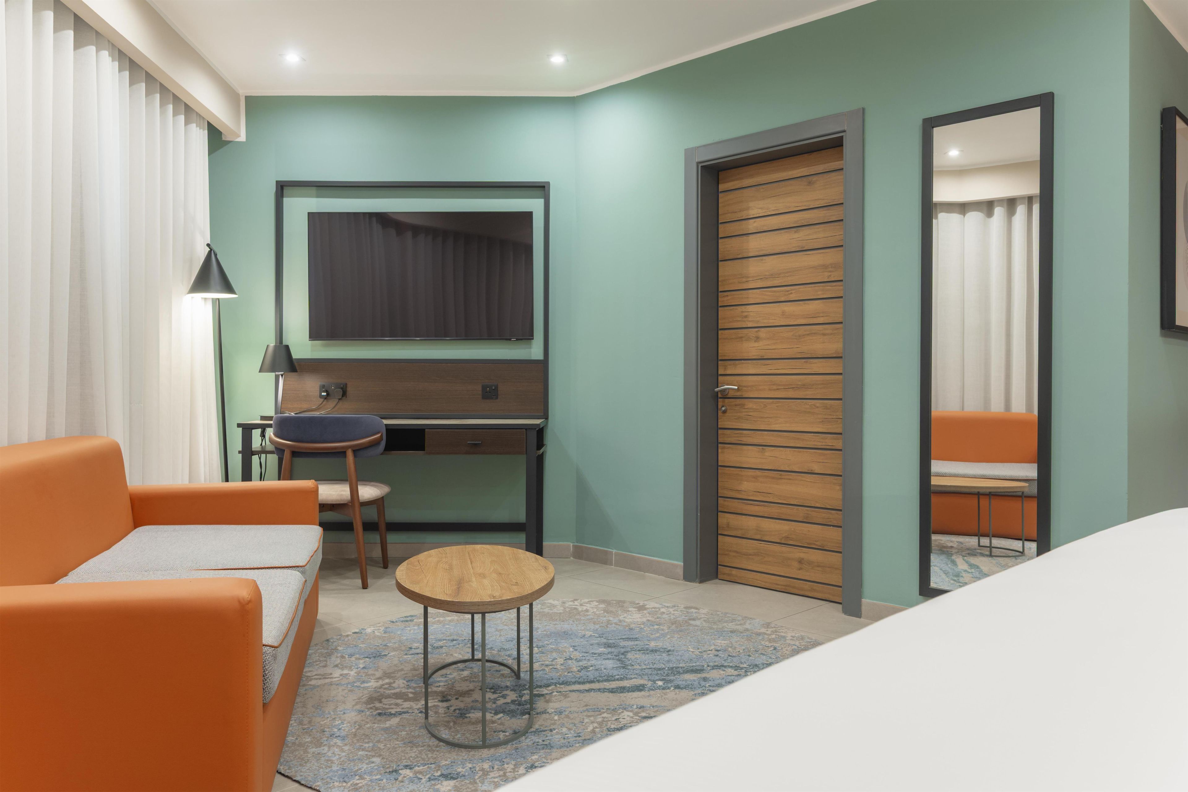 A hotel room with a bed, a desk, a chair, and a sofa.