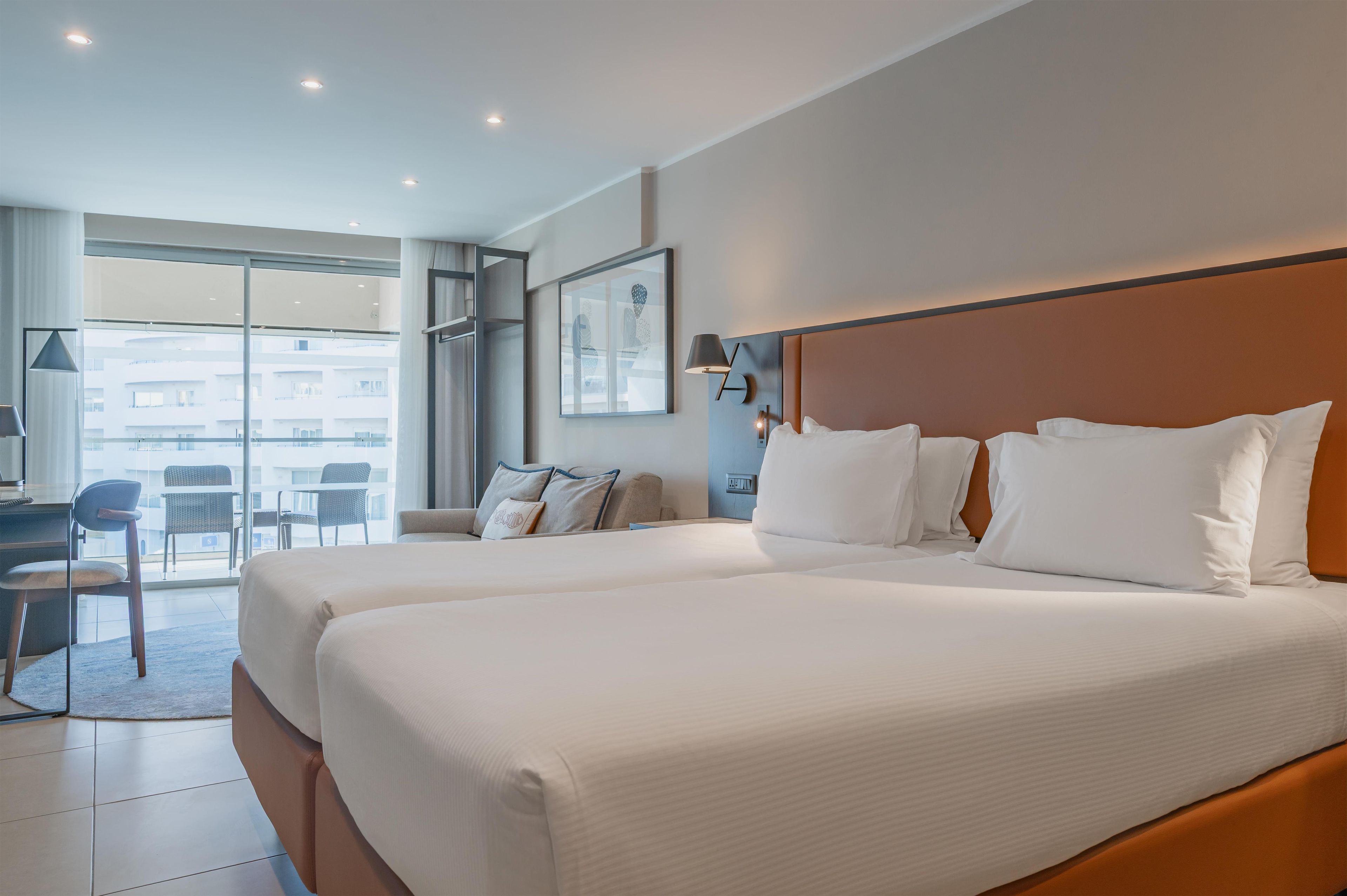 Habitación de hotel con dos camas, un escritorio y una silla.