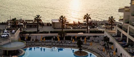 Un resort con piscina, tumbonas y vistas al mar.