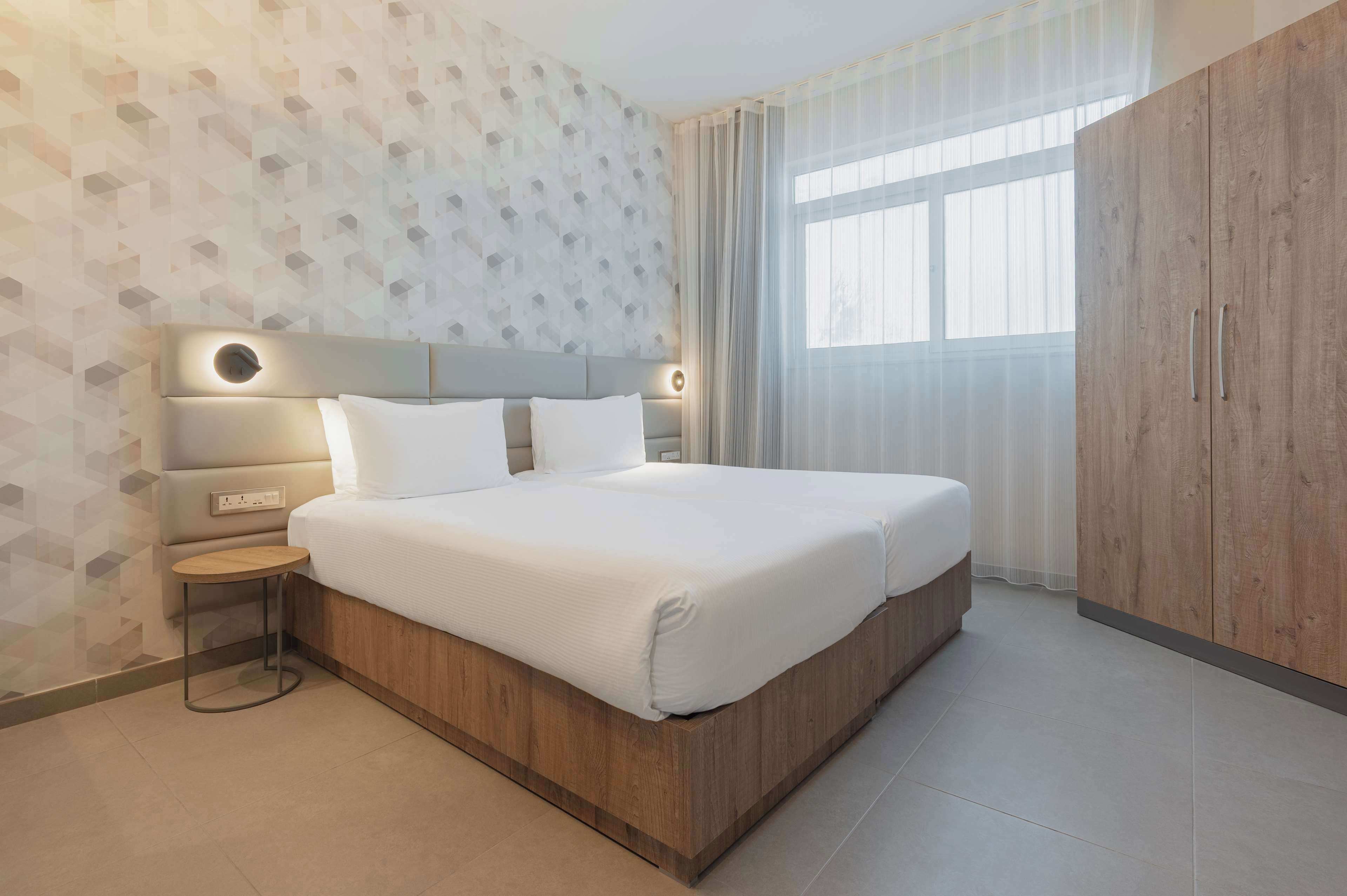 A modern bedroom with a large bed, wooden headboard, and a small bedside table.