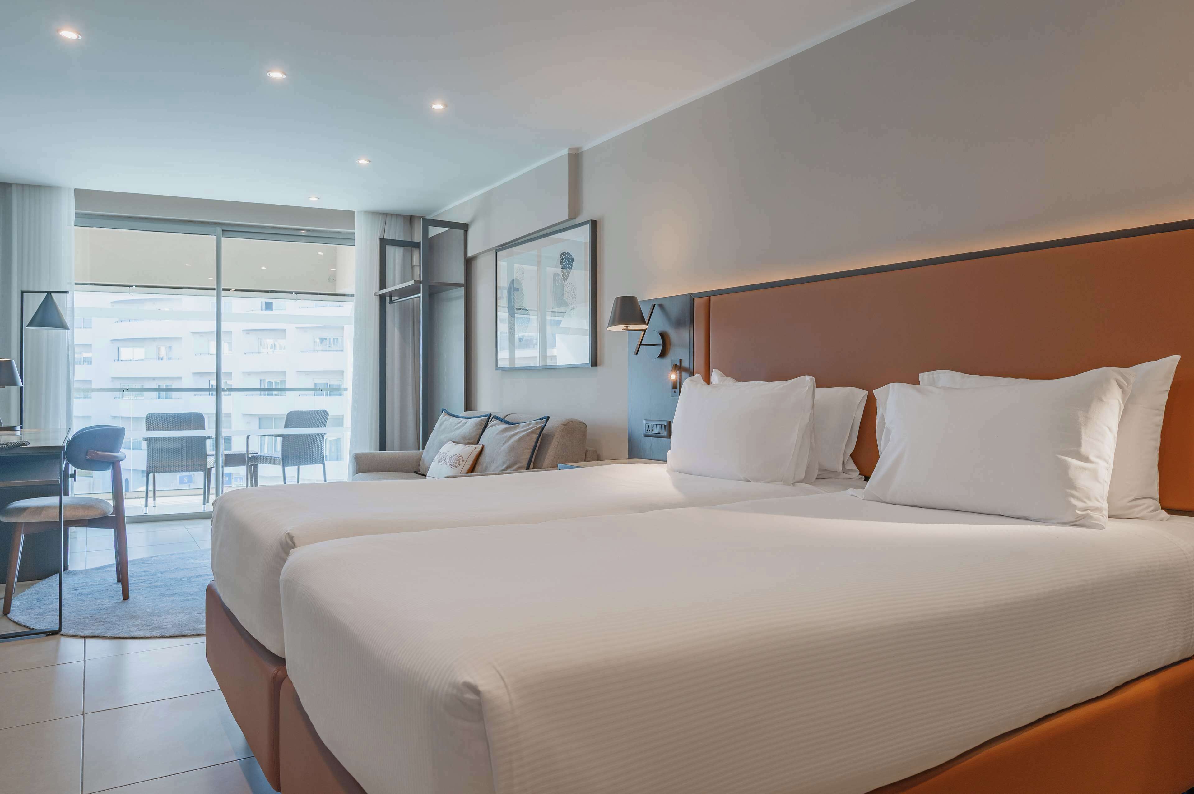 Une chambre d’hôtel avec deux lits, un bureau et une chaise.