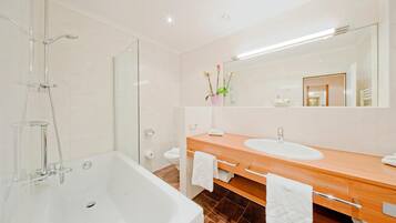 Un baño moderno con bañera, tocador doble y un espejo grande.