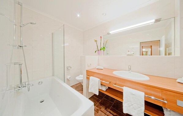 Un baño moderno con bañera, tocador doble y un espejo grande.