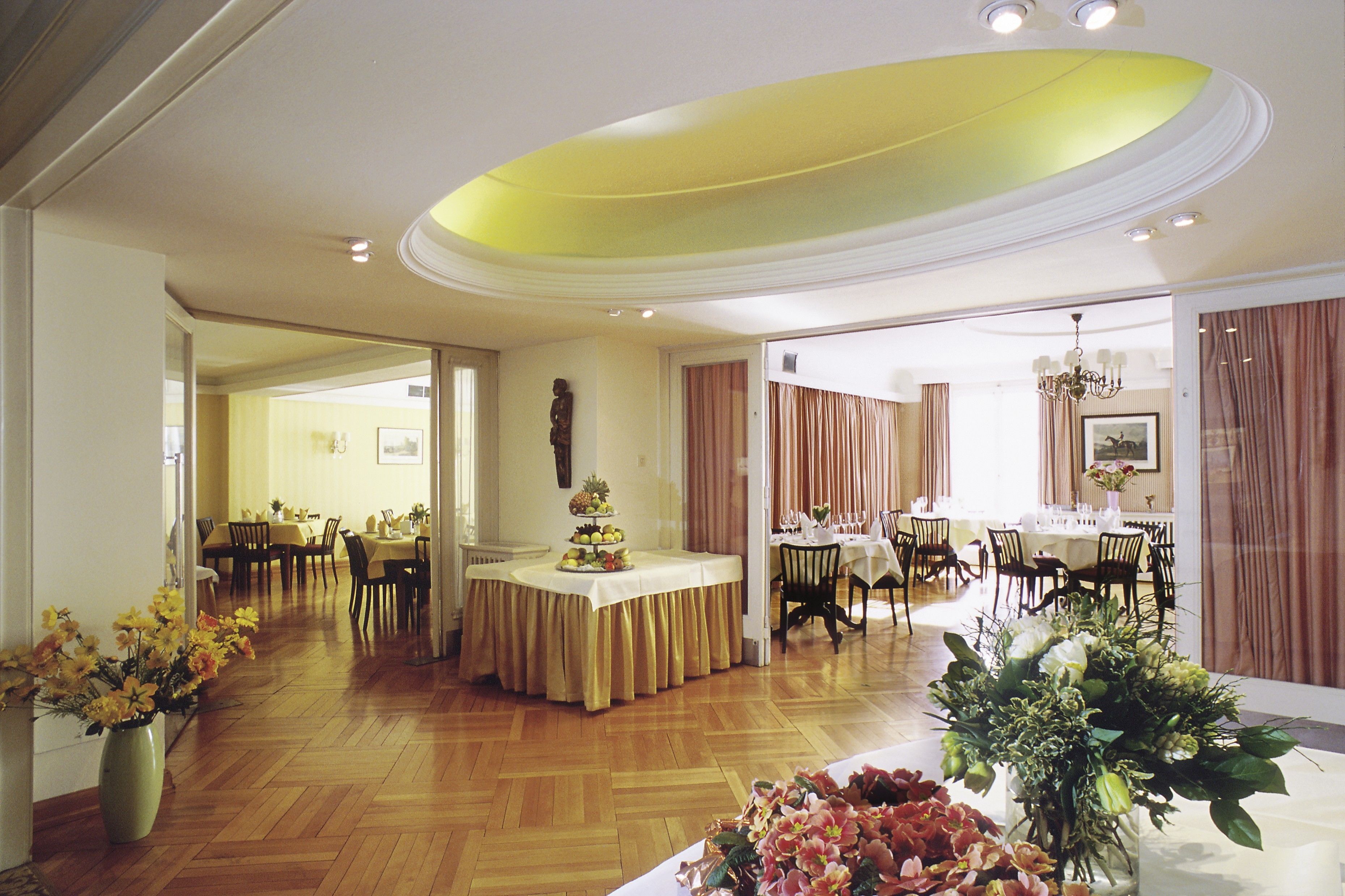 A spacious dining area with multiple tables and chairs, a central decorative display, and a chandelier.