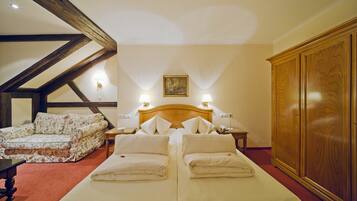 Habitación de hotel con dos camas, un sofá, un armario de madera y un cuadro en la pared.