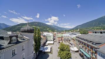A town square with historic buildings, a prominent dome structure, and surrounding green hills.
